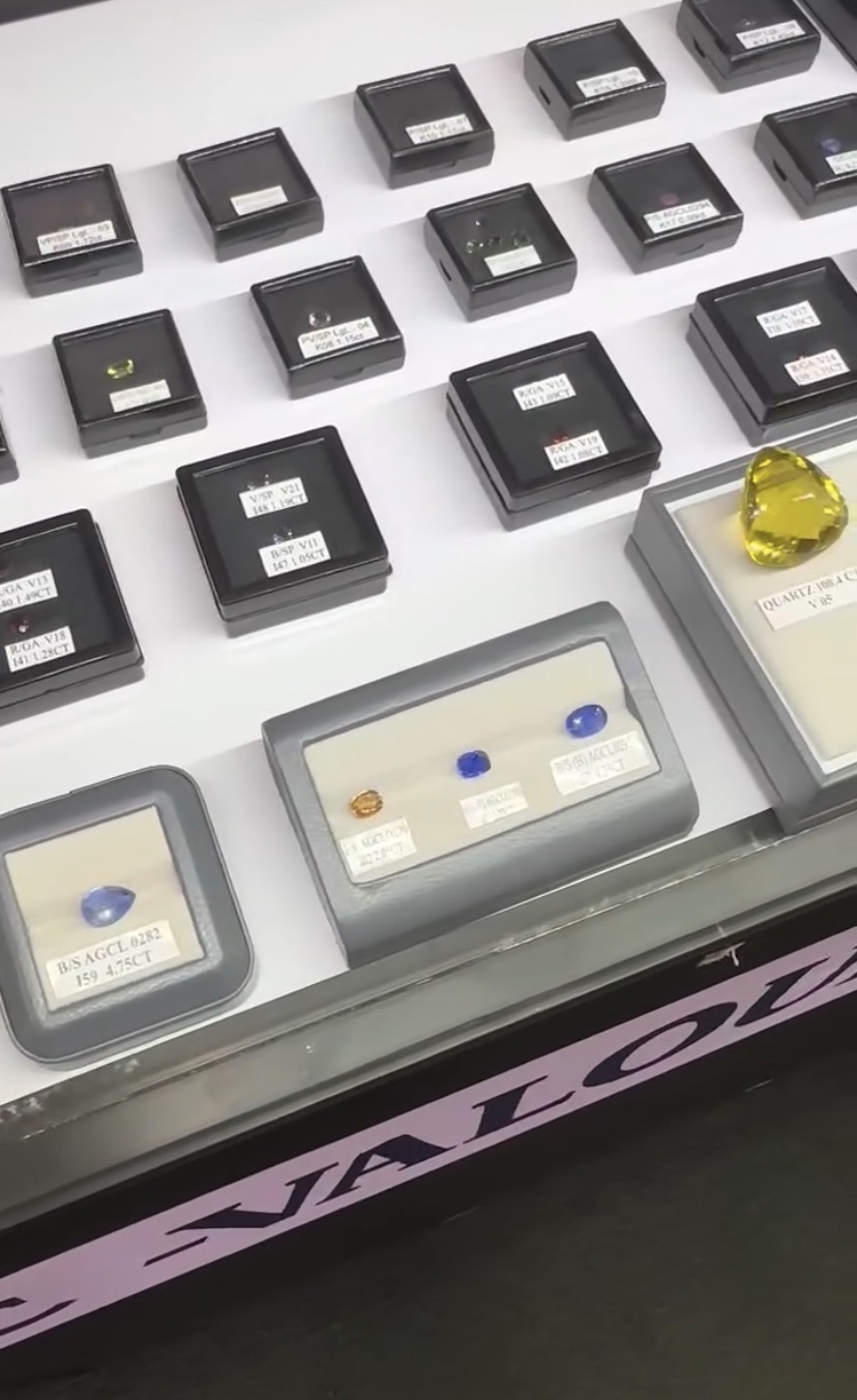 Assorted coloured gemstones arranged in labelled display boxes