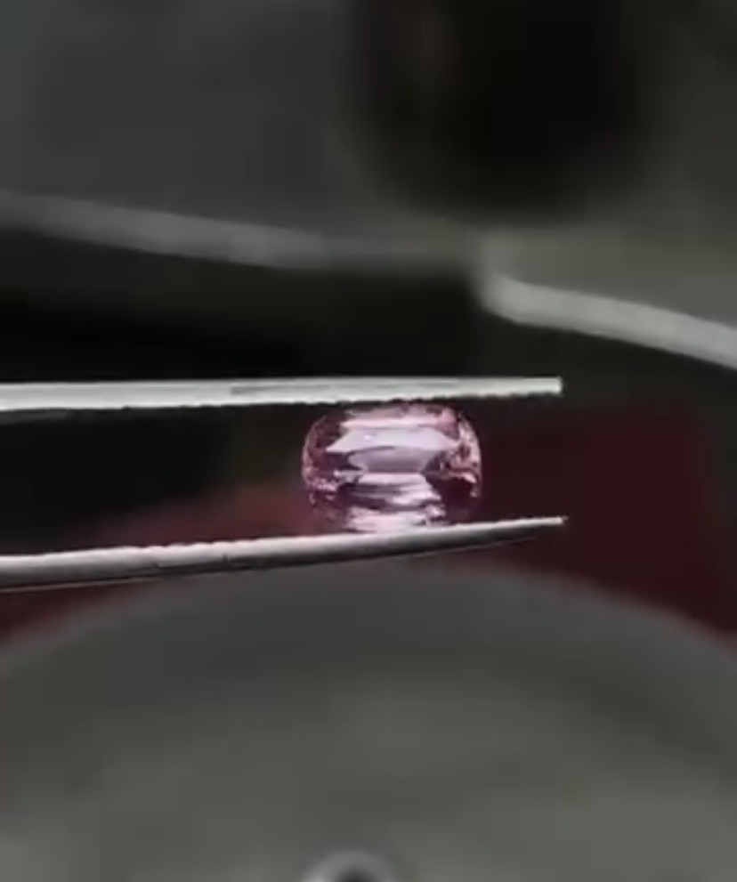 Cushion-cut pink padparadscha sapphire in tweezers